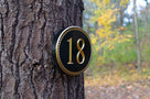 Oval house number with rope border and number 18 painted black and gold.