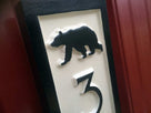 Close up of bear on vertical address number sign.