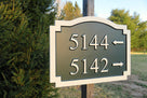 Multiple number address sign with arrows pointing direction painted green and white