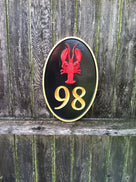 vertical oval house number with with lobster and 98 carved on it