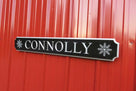 Carved quarterboard sign with last name Connolly and snowflakes on either end carved on it