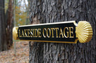 Side view of realistic 3D scallop shell with Lakeside Cottage wording painted black and gold hanging from tree