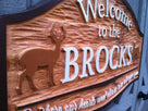 Welcome to the last name sign with deer and tag line white letters stained cedar background