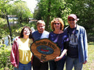 Happy family holding custom cedar camp sign