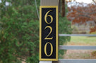 House number sign with 620 carved on it vertical position painted black and gold