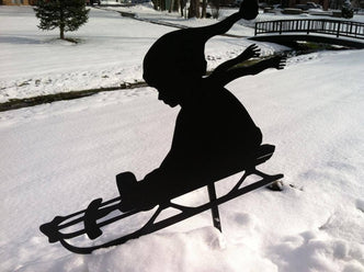 Silhouette of child going down hill in snow