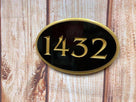 Oval shaped house number sign with 1432 carved on it painted black and gold