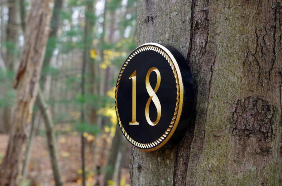 Oval house number with rope border painted black and gold.