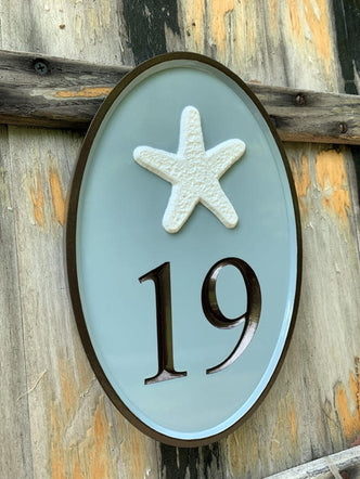 Oval house number sign with 19 and starfish carved on it