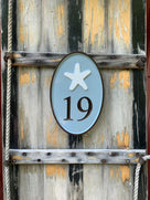 Oval house number sign with 19 and starfish carved on it painted sea foam green and white
