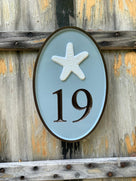 Oval house number sign with 19 and starfish carved on it painted sea foam green