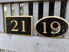Rectangle shaped house number sign with 21 carved on it and oval with 19 carved on it painted black and gold