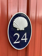 Oval house number painted navy blue and gold with number 24 and realistic scallop shell