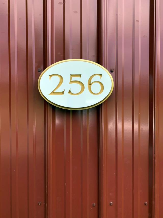 Oval shaped house number sign with 256 carved on it painted white and gold
