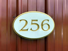 Close up picture 256 white and gold oval house number sign