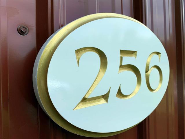 Side view of 256 white and gold oval house number sign
