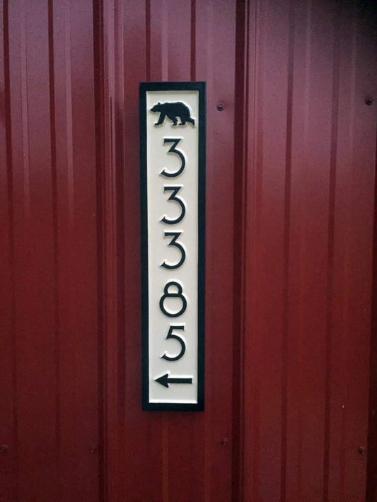 Vertical house number sign with bear and arrow.