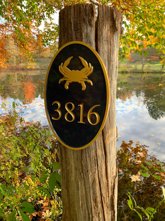 House number sign with crab and number carved on it painted black and gold
