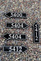 several house number signs carved on arrow shaped signs 