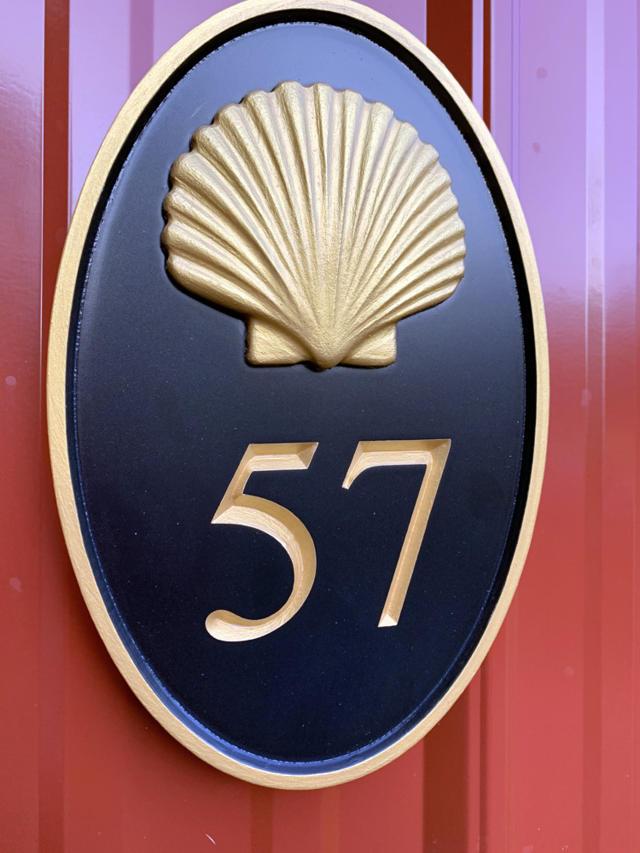 Oval house number with realistic shell and number 57 painted black and gold