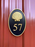 Oval house number with realistic shell and number 57 painted black and shell and numbers gold