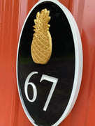 Side view of custom house number sign with pineapple carved on it