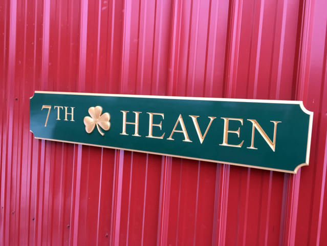 Side view of green and gold quarterboard sign with 7th Heaven carved on it and 3D shamrock