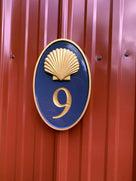 Oval house number painted naval blue and gold with number 9 and realistic scallop shell