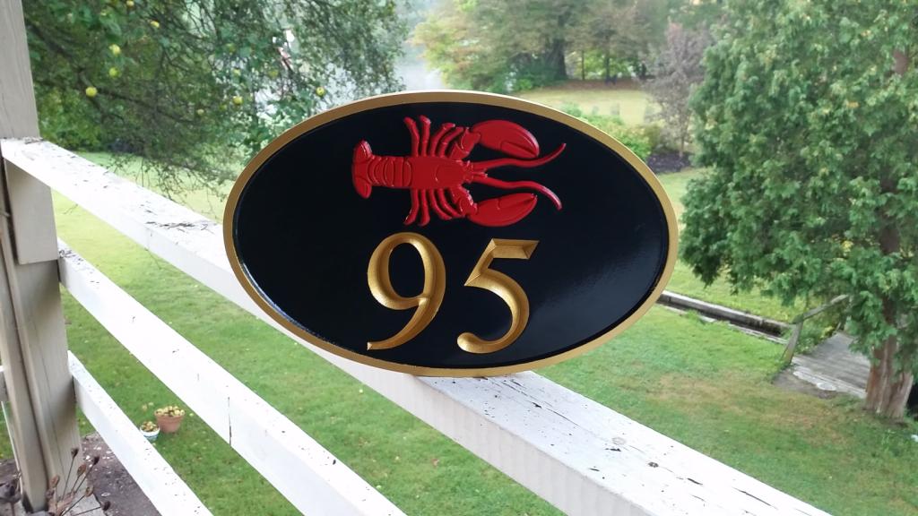 Horizontal oval house number sign with 95 and lobster carved on it