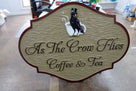Ornate shaped coffee shop sign with business name and crow carved and painted on it