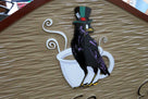 Close of up crow and tea cup on ornate shaped restaurant sign with business name and crow carved and painted on it