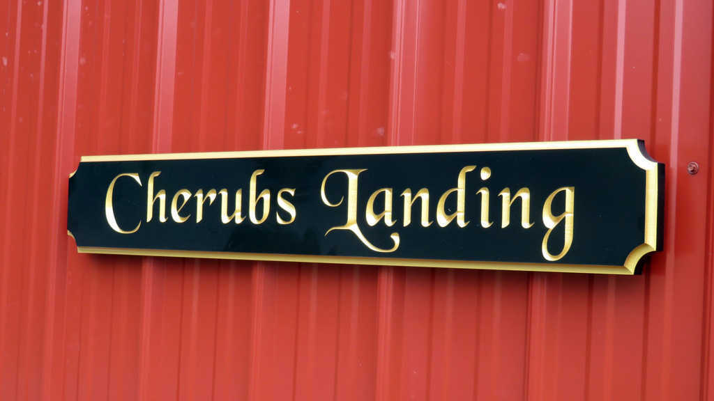 Black and gold quarterboard sign mounted on barn