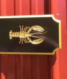Close up of gold lobster carved on quarterboard sign