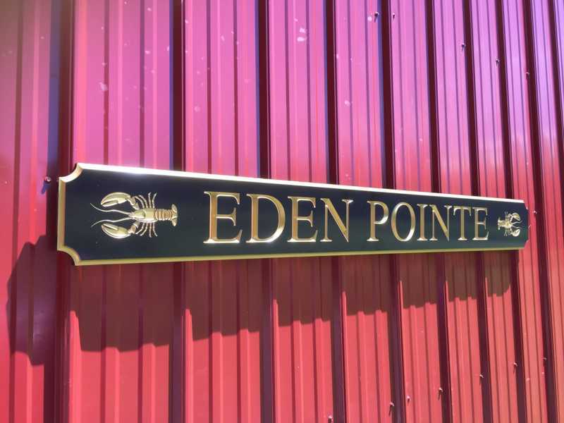 Angle view of Custom carved quarterboard with Eden Pointe and lobster carved on it