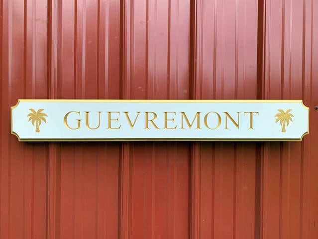 white and gold quarterboard sign mounted on barn