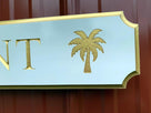 Close of of palm tree carved on quarterboard sign painted gold
