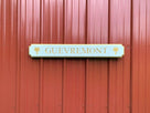 Quarterboard sign with Guevremont carved on it painted white and gold