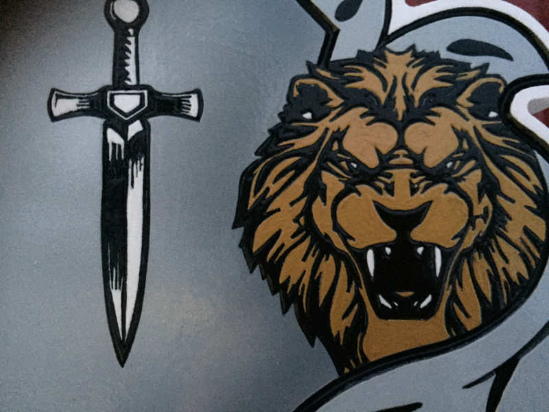 close up of sword and lion on Custom carved and painted Humbert family crest with lion heads