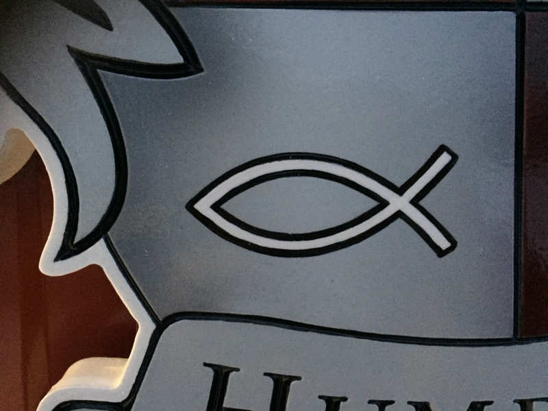 close up of fish symbol carved on custom carved and painted Humbert family crest with lion heads