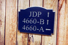 Business complex address number sign with multiple numbers and directional arrows carved on it painted blue and silver