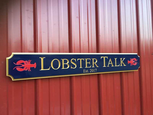 Navy blue quarterboard sign with red lobsters and Lobster Talk wording carved on it