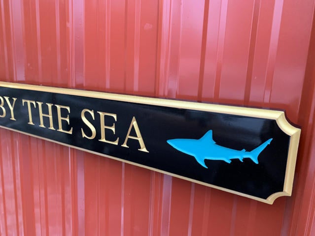 Quarterboard with McT by the Sea carved on it and close up picture of shark on sign