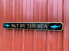 Quarterboard with McT by the Sea carved on it and sharks carved on it painted black and gold