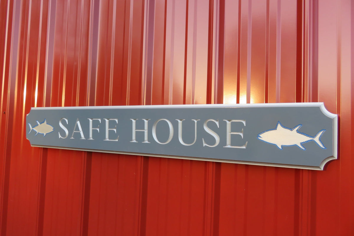 Quarterboard sign with Safe House and sharks carved on it