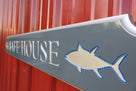 Quarterboard sign with Safe House and sharks carved on it side view