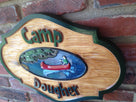 Camp sign with last name and canoe paddler on water