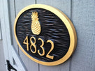 side view of carved house number sign with pineapple painted black and gold