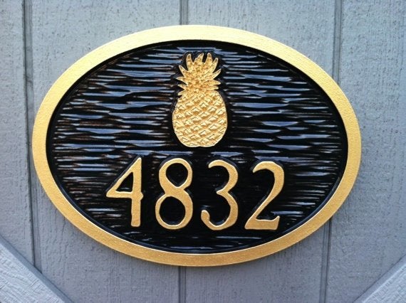 carved house number sign with pineapple painted black and gold