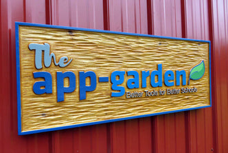 Small business sign carved from cedar wood with the app garden carved on it