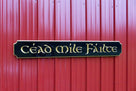 Black and gold quarterboard with Cead Mile Failte  carved on it in gaelic font